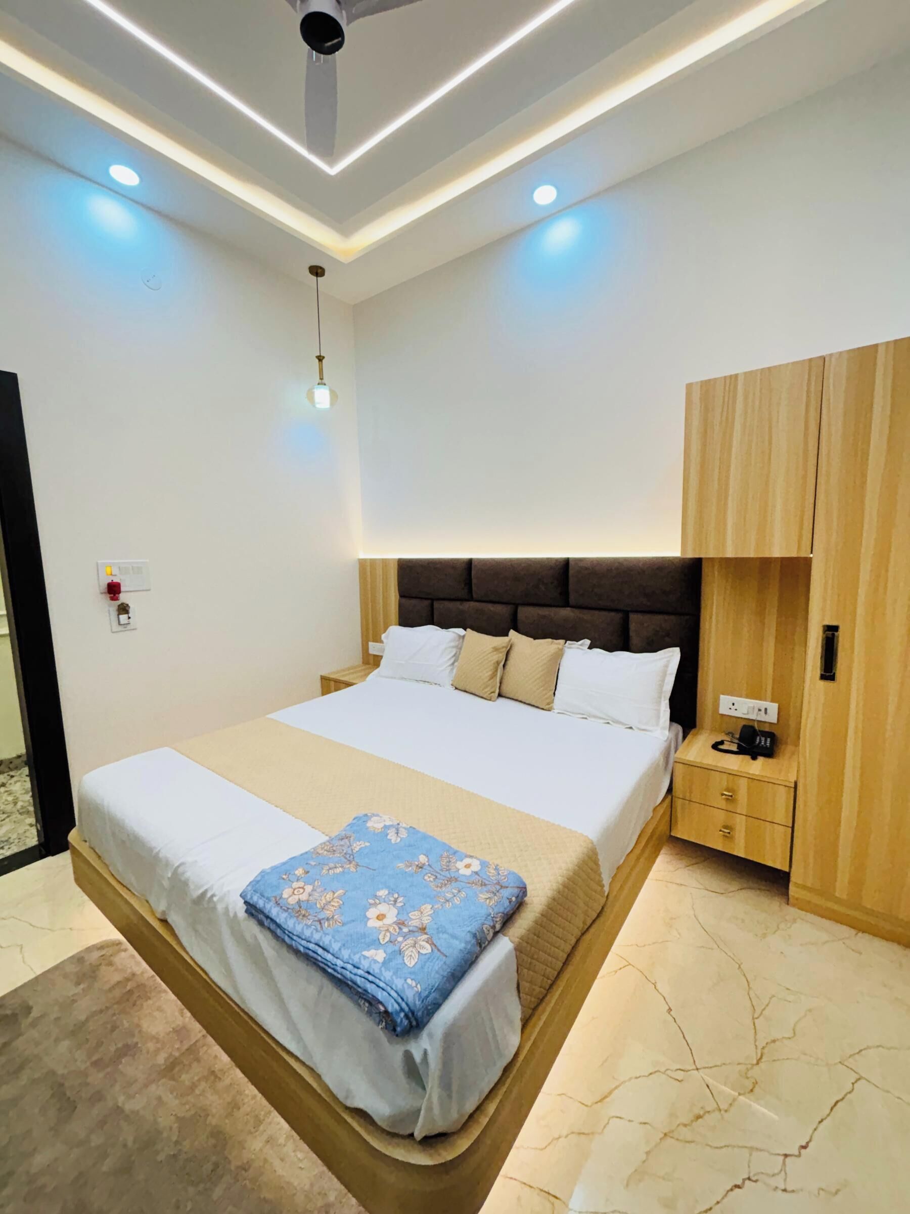 A modern bedroom with a large bed, bedside tables, a wardrobe, and recessed ceiling lighting.