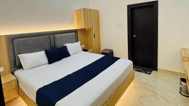 A modern bedroom with a bed, bedside tables, a lamp, an air conditioning unit, and a ceiling fan. - GS Palace Ayodhya (Ayodhya)