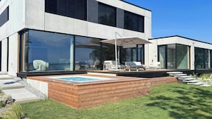 Una casa moderna amb piscina, mobiliari exterior i grans finestres.