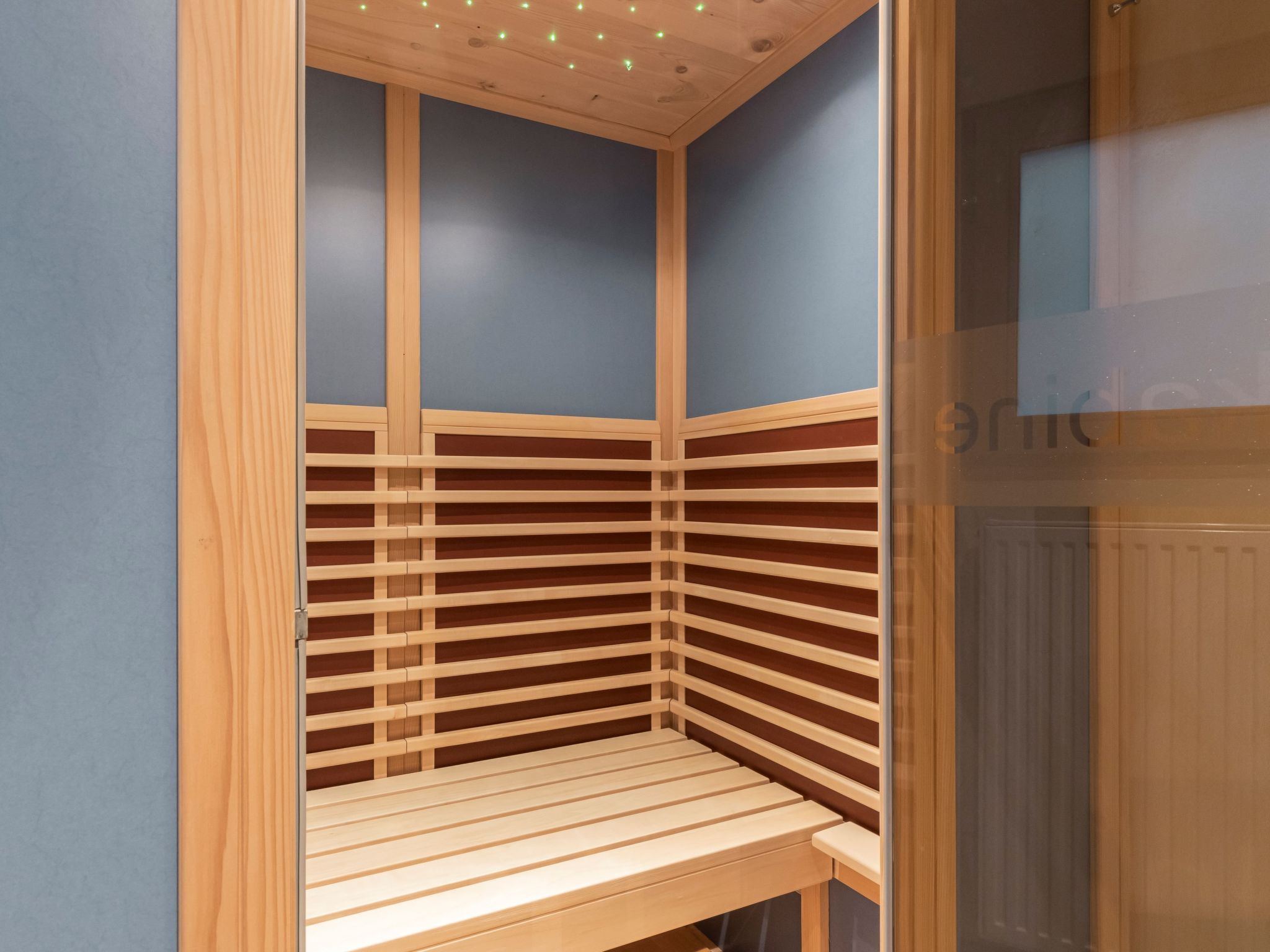 Un petit sauna d’angle avec des lambris en bois et un banc.