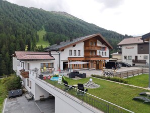 A two-story building with a balcony, outdoor seating, and a pool. - Soliva Hotel & Apartments by MEIN SAMNAUN – MOUNTAIN HOMES, (Samnaun-Compatsch) by Interhome (Samnaun)