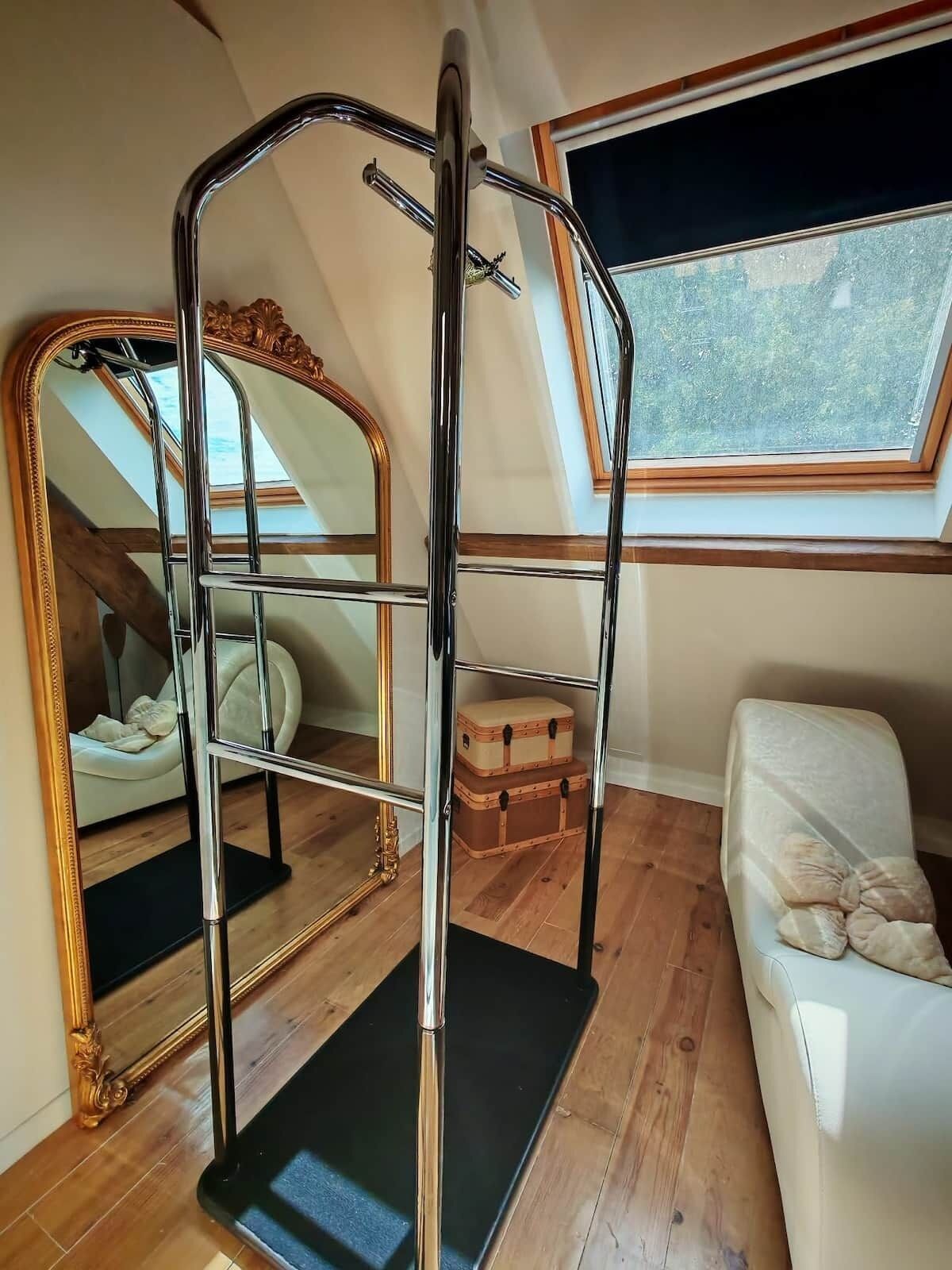 Een kamer met een stapelbed, een grote spiegel, een raam met uitzicht en een houten vloer.