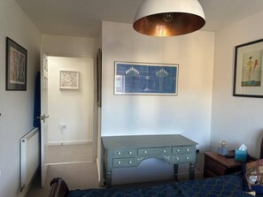 A room with a bed, a desk, a radiator, a framed picture, and a hanging light fixture. - Super Comfy, Convenient two Bedroom Apartment (Corsham)