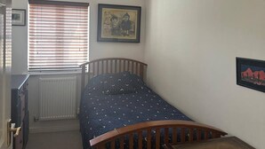 A bedroom with a single bed, a radiator, a window with blinds, a desk, and a wall-mounted picture. - Super Comfy, Convenient two Bedroom Apartment (Corsham)