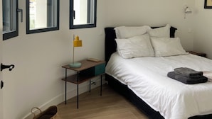 A bedroom with a bed, bedside table, lamp, and a window.