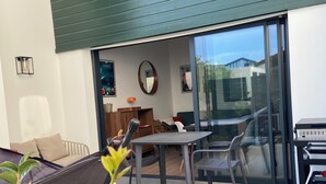 An outdoor patio area with a dining table, chairs, a sofa, and potted plants.