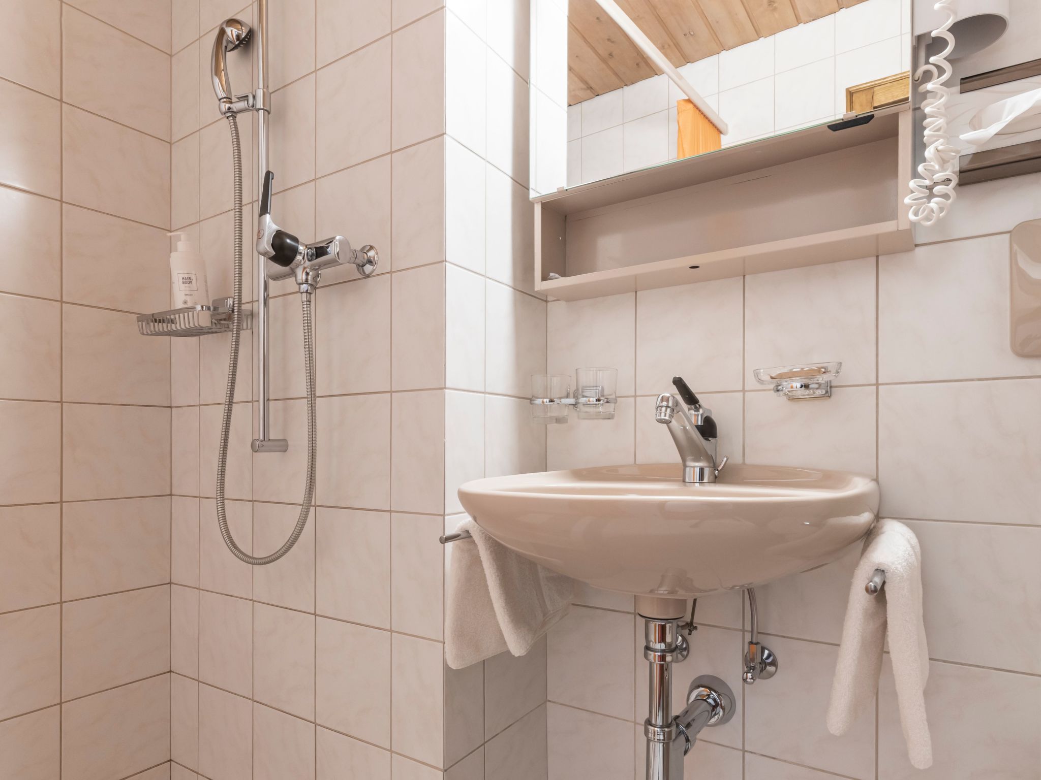 Ein Badezimmer mit Dusche, Waschbecken und Spiegel.