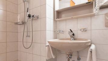 Ein Badezimmer mit Dusche, Waschbecken und Spiegel.