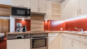 Una cocina moderna con electrodomésticos de acero inoxidable, encimeras de madera y una pared de acento roja.