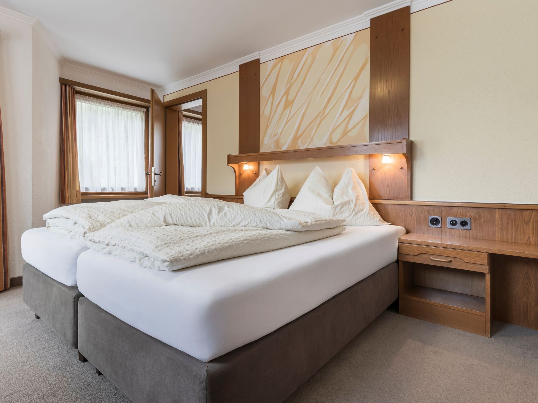 A double bed with a headboard, bedside tables, and a large mirror.