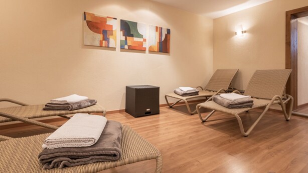 Una habitación con tres sillones de mimbre, un altavoz negro pequeño y arte abstracto en la pared.