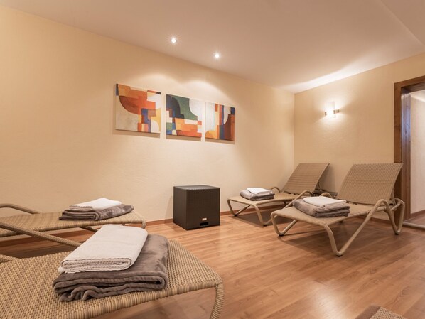 A room with three wicker lounge chairs, a small black speaker, and abstract wall art.