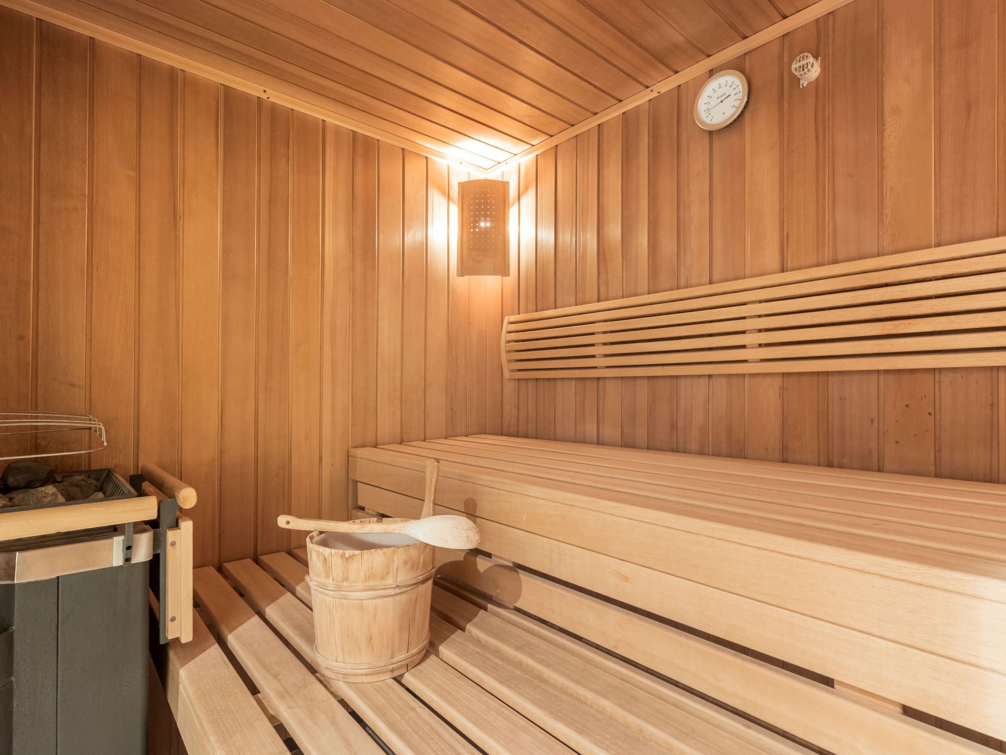 Un sauna avec des bancs en bois, un seau en bois et un appareil de chauffage.
