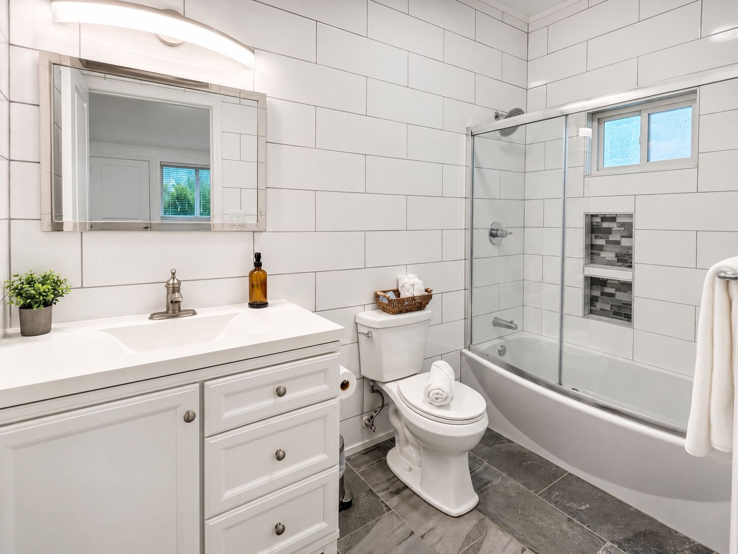 A modern bathroom with a glass shower enclosure, a white toilet, and a vanity with a sink and drawers.