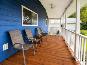 A covered porch with wooden flooring, a white railing, and a blue exterior wall. - Lakefront Cabin | 3BR | Centrally Located (Perry)