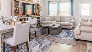 A living room with a sofa, coffee table, TV, and decorative items. - Woodridge - Bedroom with Private Outdoor Bathroom (Porter)
