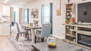 A modern living room with a dining area, a fireplace, and a TV. - Woodridge - Bedroom with Private Outdoor Bathroom (Porter)