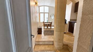 Un couloir menant à une salle à manger équipée d’une table et de chaises, d’une fenêtre et d’une porte.