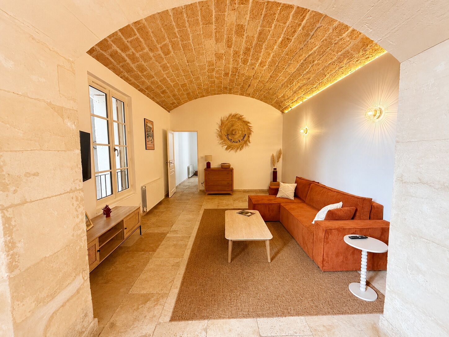 A spacious living room with a high arched ceiling, a wooden bench, a sofa, a coffee table, and a small side table.