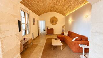 A spacious living room with a high arched ceiling, a wooden bench, a sofa, a coffee table, and a small side table.