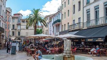 A public square with outdoor seating, a fountain, and buildings with cafes.