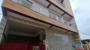 A multi-story building with a red gate, a tiled wall, and a signboard. - Sehrawat Guest House (Sakrai)