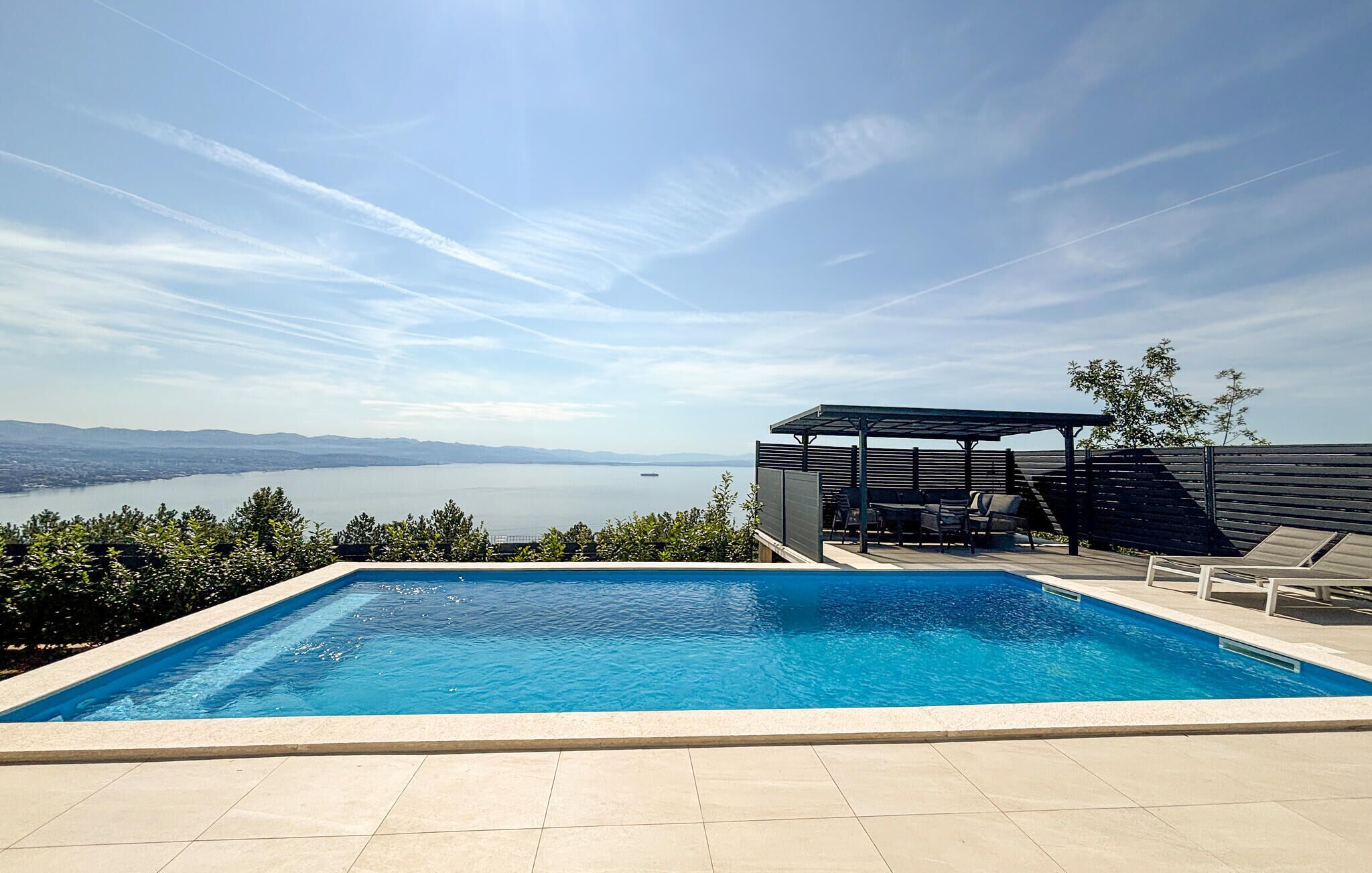 A swimming pool with a view of a lake and distant mountains.
