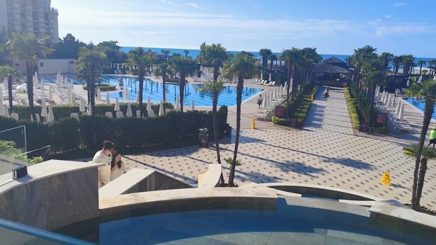 Ein Poolbereich eines Resorts mit mehreren Schwimmbecken, Palmen und blauem Himmel.