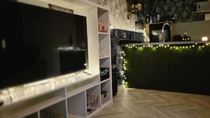 A modern kitchen with a built-in TV, a bar area with green lighting, and a herringbone wood floor. - Pet Friendly 2-bed Apt, Sleeps 3 With Parking (Doncaster)