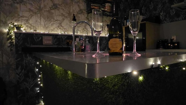A bar area with a marble countertop, two glasses, a bottle, and a sign. - Pet Friendly 2-bed Apt, Sleeps 3 With Parking (Doncaster)