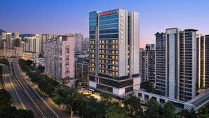 Un hotel moderno de gran altura, con un llamativo letrero 'Champion', rodeado de otros edificios altos y una avenida con múltiples carriles.