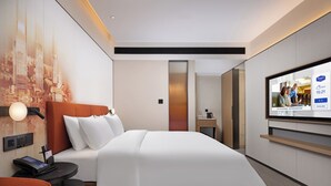 Una habitación de hotel moderna con cama, televisión, escritorio con teléfono y televisión montada en la pared.