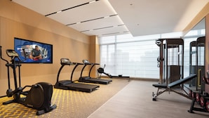 Un gimnasio con cintas de correr, una elíptica y una estructura para sentadillas.