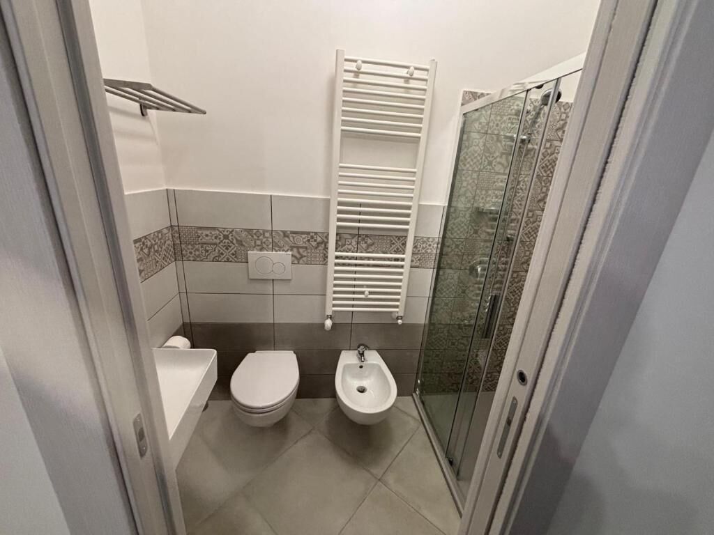 Un baño con inodoro, bidé y cabina de ducha de vidrio.