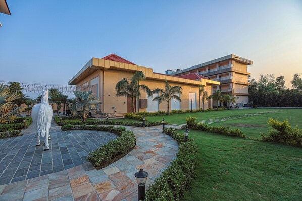 Un hotel con un patio, una estatua y un jardín bien cuidado.