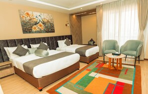 Una habitación de hotel con dos camas, una mesita pequeña y una silla.