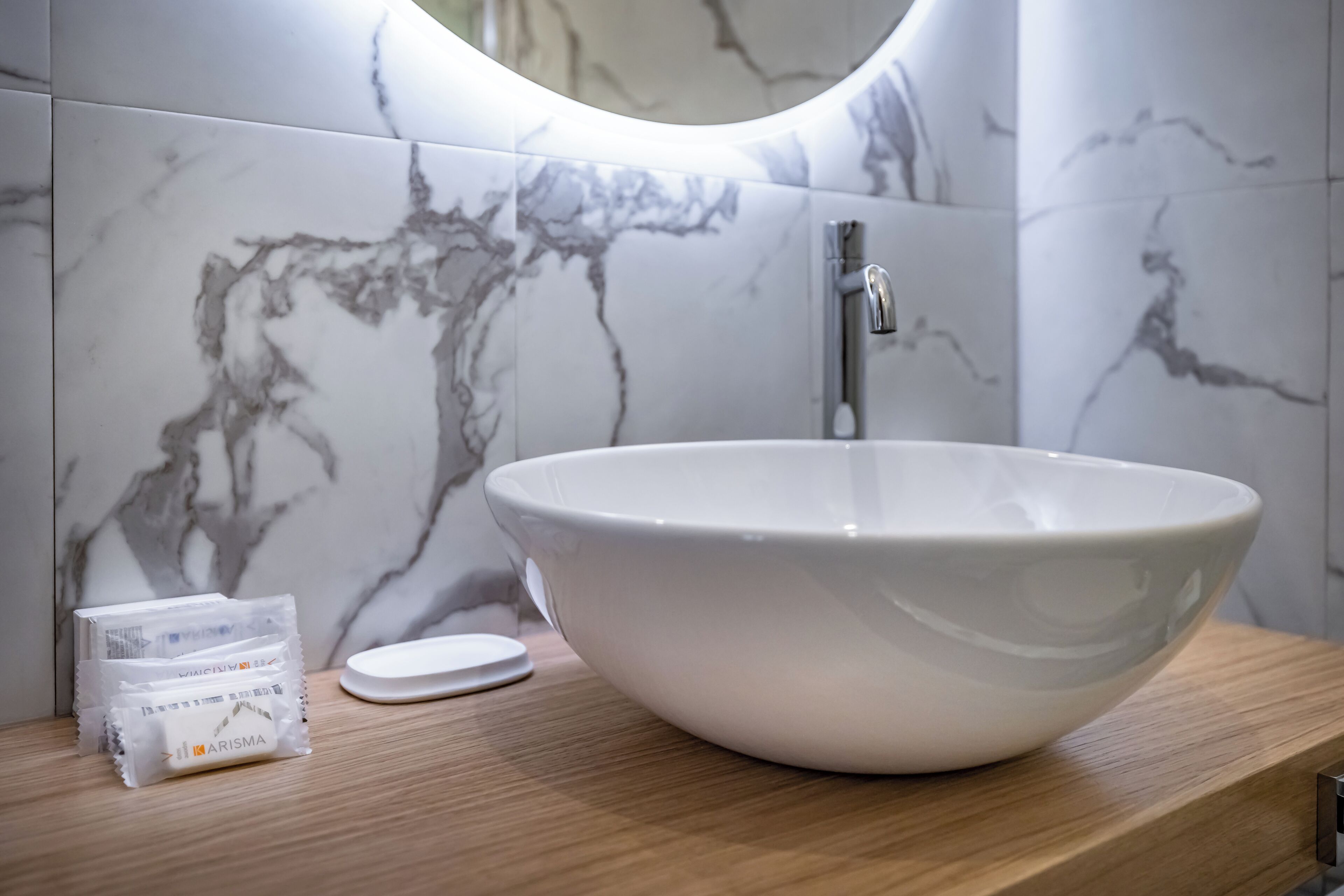 A bathroom with a white marble sink, a mirror, and a wooden countertop.