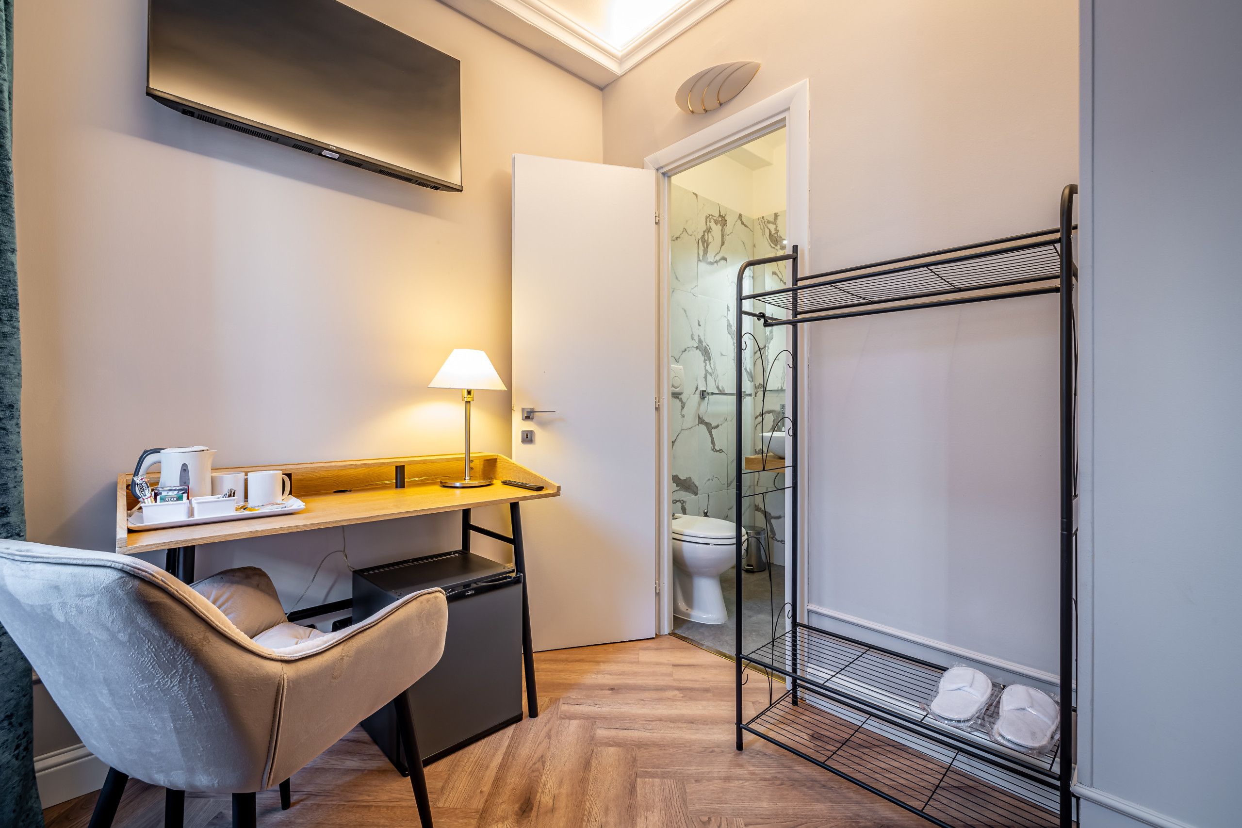 Une chambre d’hôtel compacte, équipée d’un bureau, d’une chaise et d’une petite kitchenette.