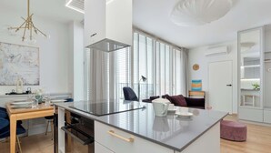 Eine moderne Küche mit einer zentralen Kochinsel, einem Esstisch mit Stühlen und einem Sofa im Wohnbereich.