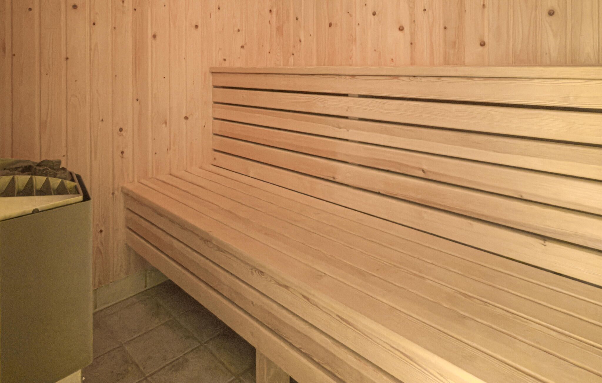 Un banc en bois, doté d’assises composées de lattes horizontales, adossé à un mur en bois.
