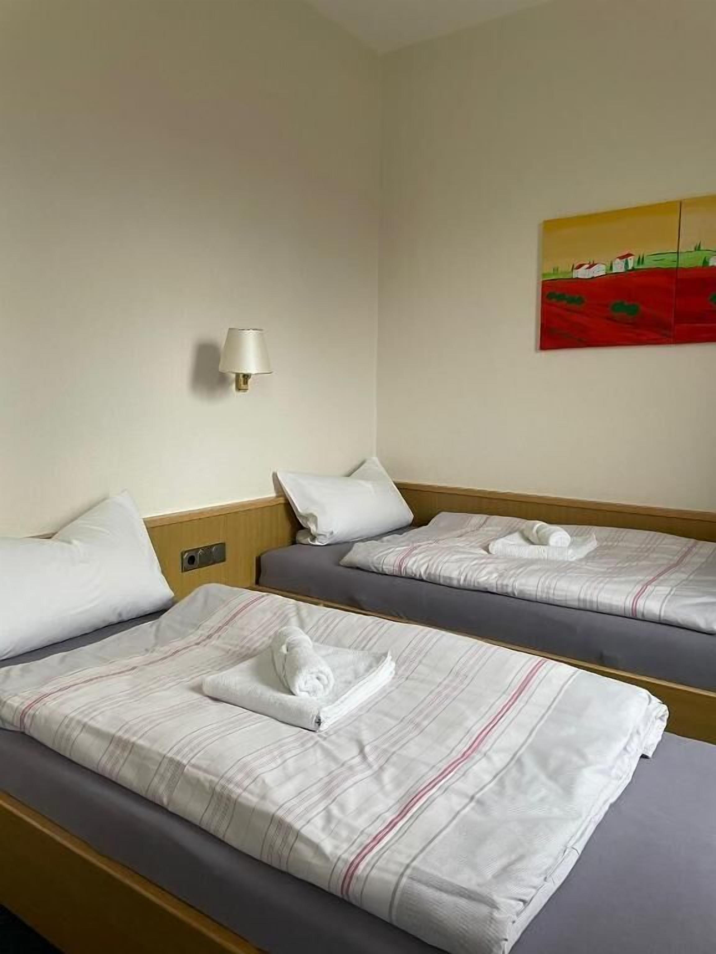 Habitación de hotel con dos camas, una lámpara de pared y un cuadro.