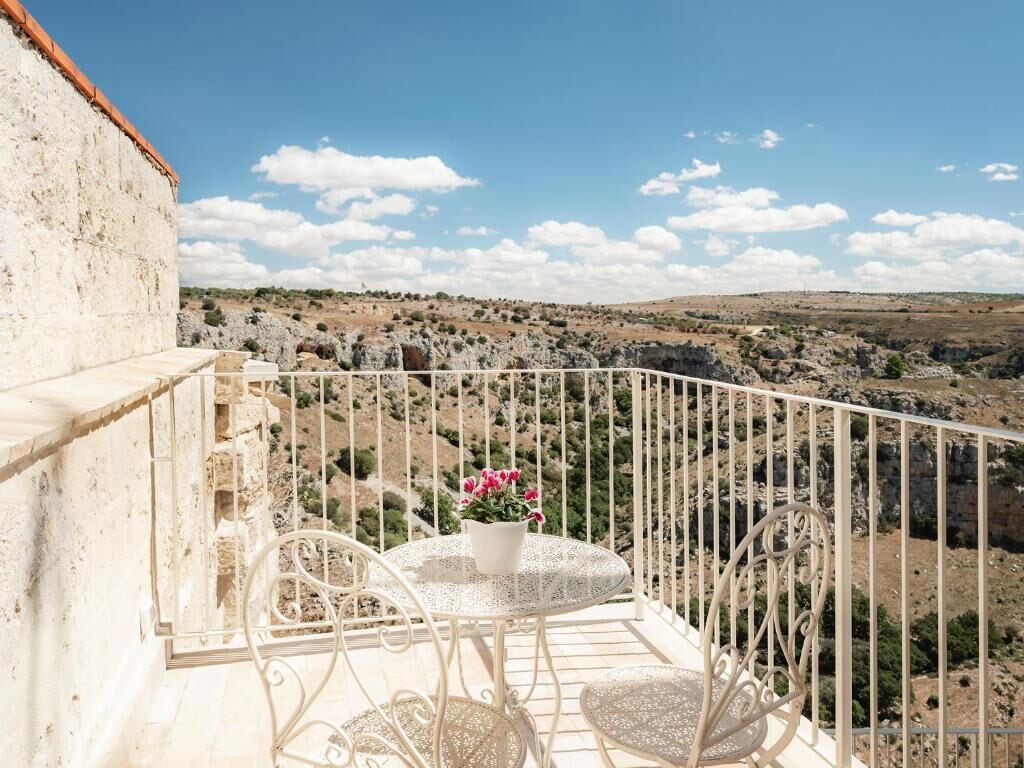 A balcony with a table and chairs, overlooking a rocky landscape.
