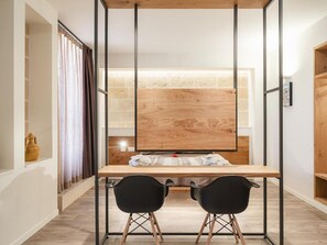 Une pièce moderne avec un bureau en bois, deux chaises noires et une grande fenêtre avec des rideaux.