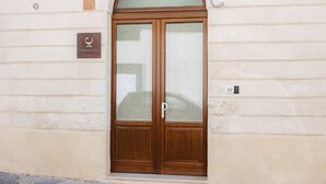 Eine doppelte Holztür mit Glasschilden, einer Plakette und einem kleinen Fenster darüber.