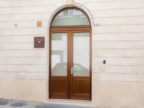 Une porte à deux battants en bois, avec des panneaux de verre, une plaque et une petite fenêtre au-dessus.