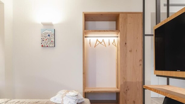Ein Schlafzimmer mit einem Bett, einem Holzschrank, einem Fernseher und einem Wandbild.