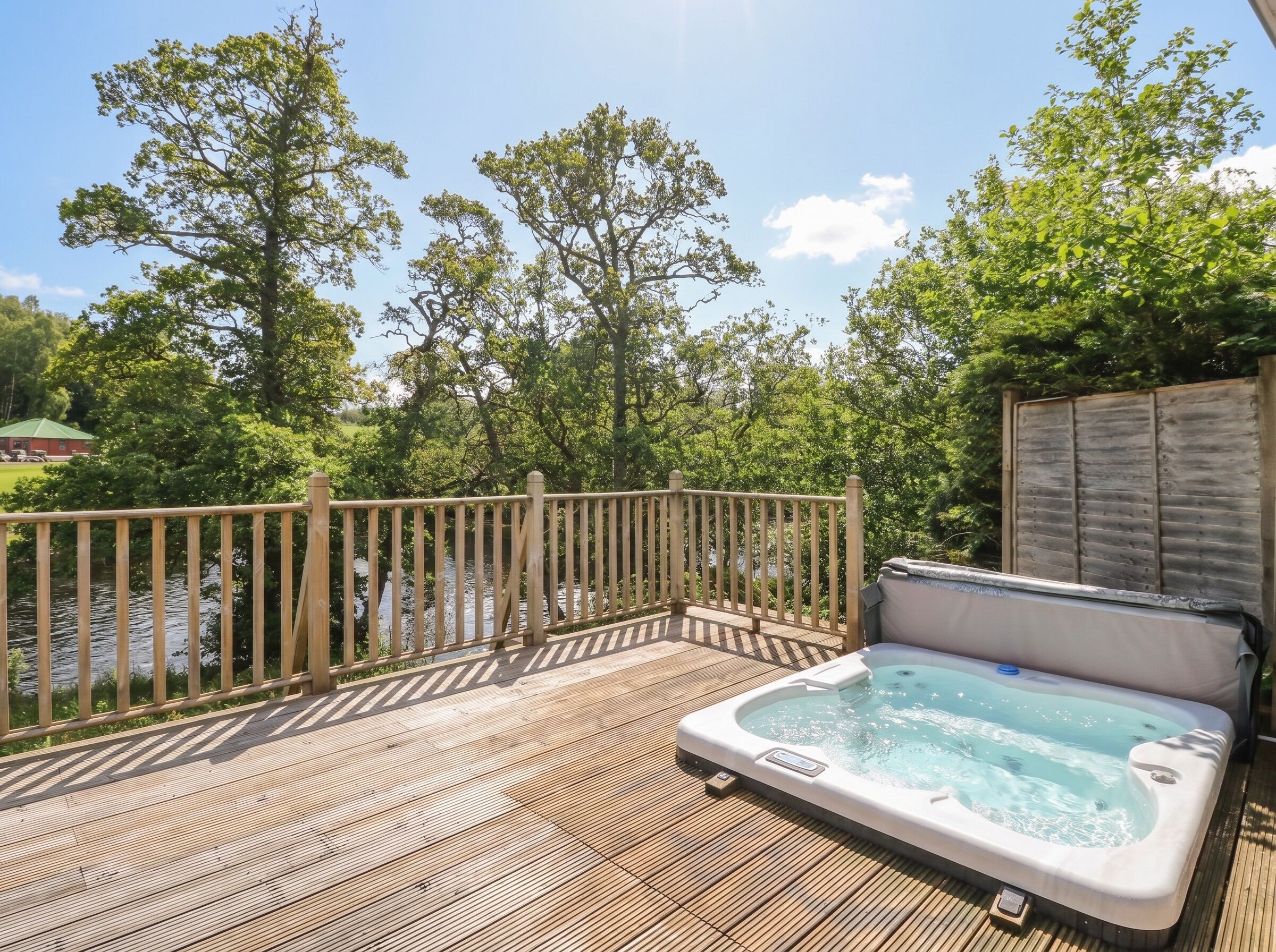 A wooden deck with a hot tub and a view of a river.