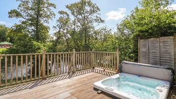 A wooden deck with a hot tub and a view of a river.