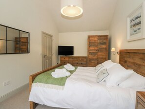 Ein ordentlich eingerichtetes Schlafzimmer mit Bett, Fernseher, Kleiderschrank und Spiegel.