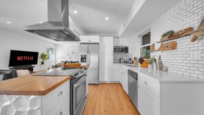 Une cuisine moderne dotée d’un îlot central, d’appareils électroménagers en acier inoxydable et d’un téléviseur à écran plat.